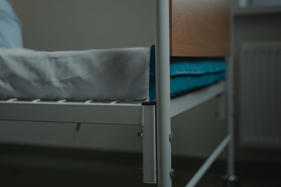 Hospital-style bed with rail and white linens