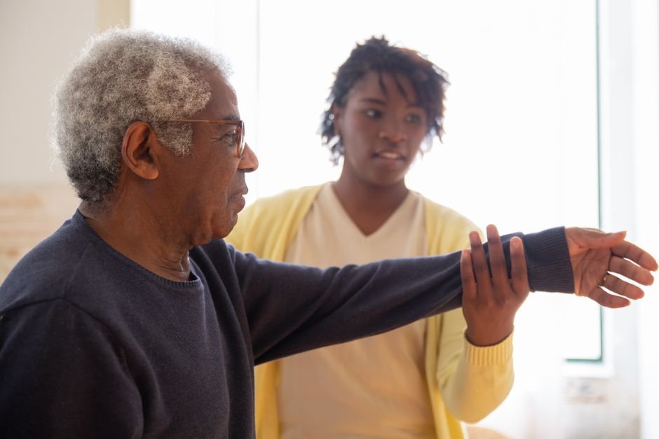 Caregiver assisting elderly man with movement