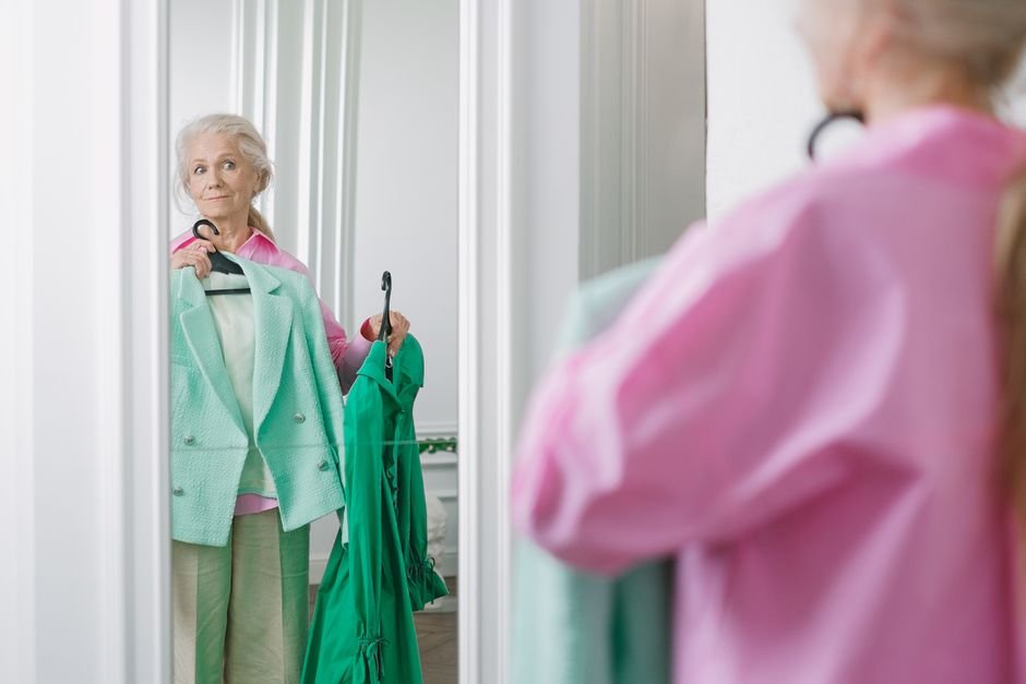 Elderly woman choosing clothes in front of a mirror