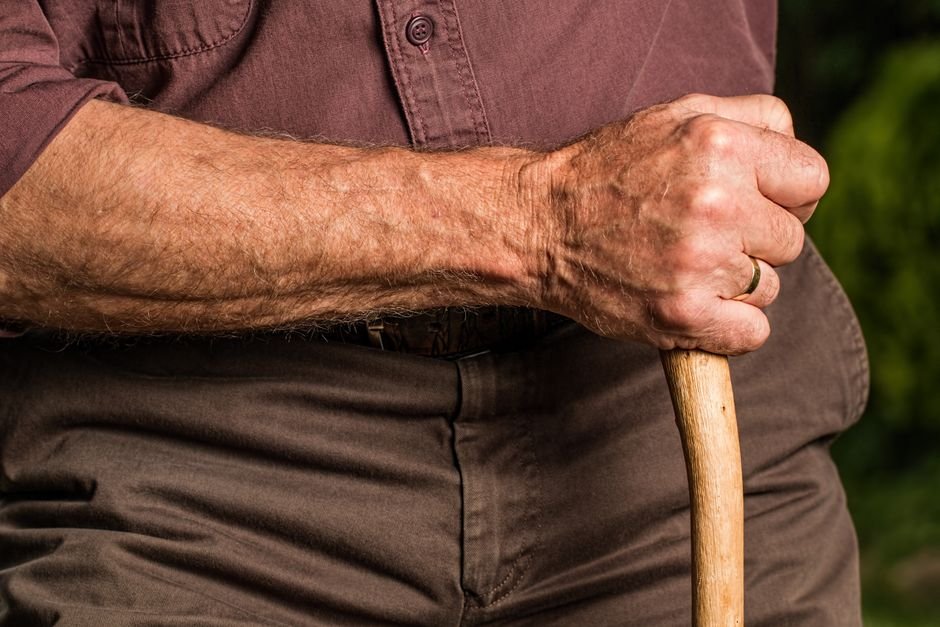 Senior adult's hand gripping a wooden walking cane